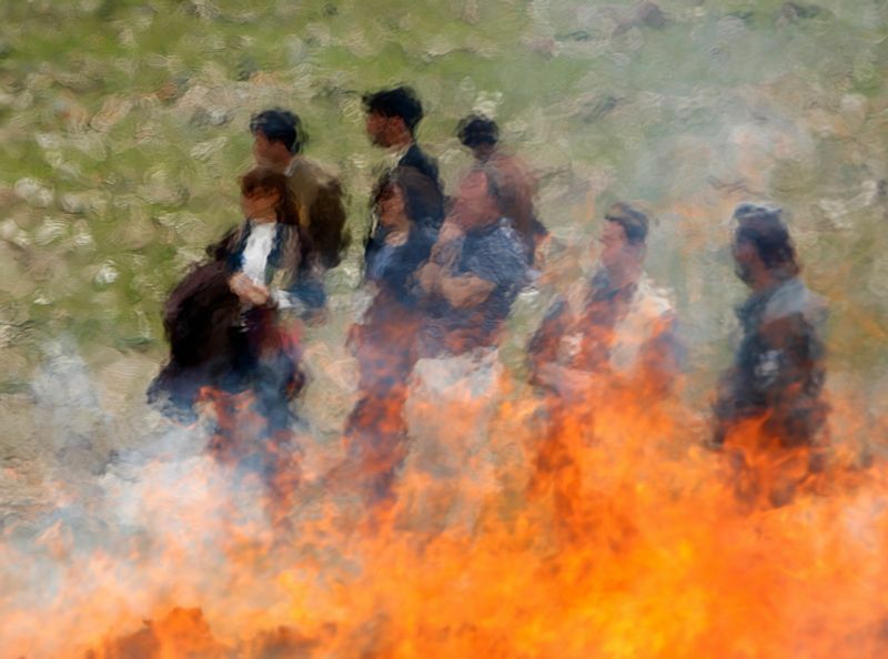 2009年4月26日、カブールで火にかけられた違法な麻薬を見るアフガニスタン人と外国人の関係者。アフガン麻薬対策省は、アヘンやハシッシュを含む6トン以上の麻薬を焼却した。