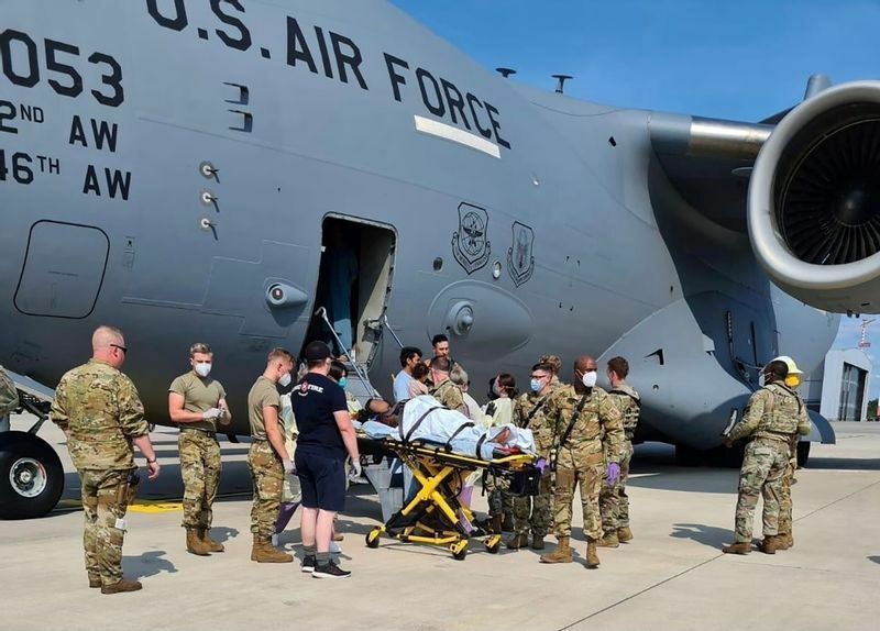 8月21日、ラムシュタイン空軍基地に着陸した米空軍のC-17輸送機から、機内で出産したアフガン人の母親が家族と一緒に降りてくるところ。医療支援員が手助けしている。