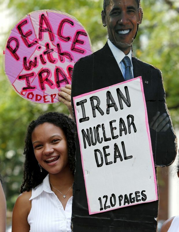 2015年8月、ホワイトハウスの外で行われたイランとの核合意を支持する集会。和解と平和をもたらしたオバマ大統領のダンボール写真の横で、笑顔を見せる反戦活動家。