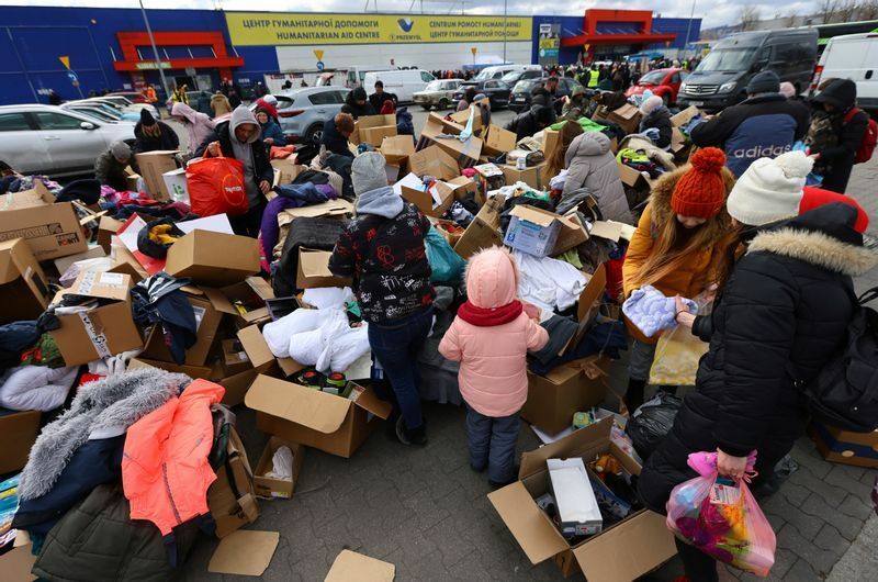 難民のための仮設宿泊施設の外で寄付された衣類を探す人々。2022年3月8日、ポーランド・プルゼミシル。