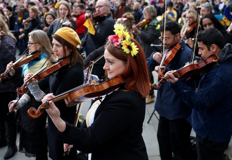 3月6日、ロンドンのトラファルガー広場で行われた抗議デモで。オーケストラのフラッシュモブ「Music for Peace」で演奏する音楽家たち。ウクライナの象徴の花飾りを付けて。