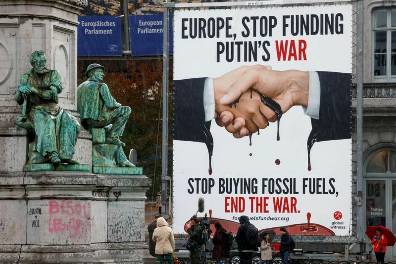 9月27日、ブリュッセルの欧州議会の外で、「ヨーロッパ、プーチン戦争への資金提供をやめろ」「化石燃料を買うのをやめろ。戦争を終わらせろ」と書かれた看板の隣に立つ活動家とメディアの人たち。