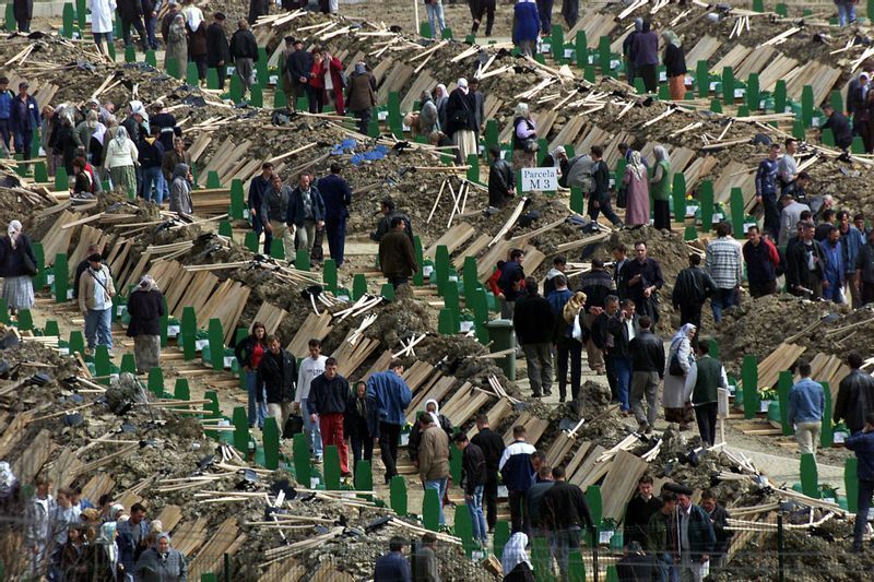 2003年年3月、スレブレニツァの虐殺で犠牲になった8000人のイスラム教徒の親族が、掘ったばかりの墓の横に並ぶ棺の間を歩き、親族のものを探している。確認された最初の犠牲者600人の埋葬。