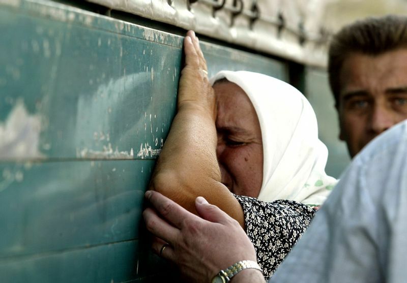 棺にすがって泣く女性。2004年、確認された犠牲者338人を遺体安置所から墓地へ移し埋葬式が行われる。