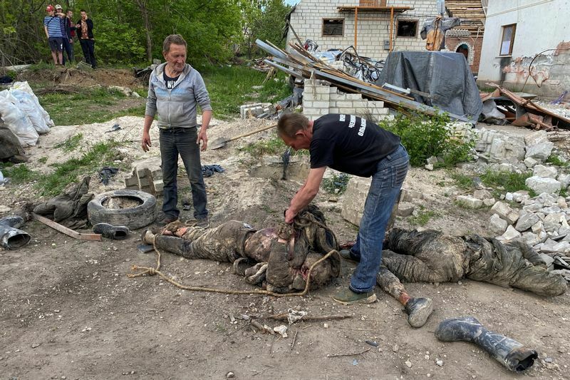 ウクライナ軍に奪還された後、ハリコフ地方のマラ・ロハン村の集団墓地で見つかったロシア兵の遺体を集めるボランティアたち。5月19日。