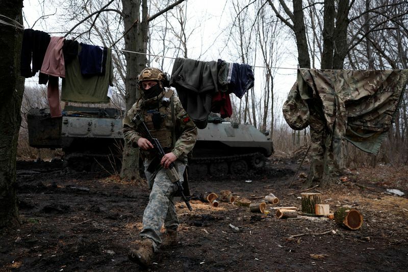 ロシアのウクライナ攻撃が続く中、ウクライナ・バフムトの前線で激しい砲撃が行われ、洗濯物の下を歩く第43重砲兵旅団のウクライナ人兵士（2022年12月26日撮影）。REUTERS/Clodagh Kilcoyne (ウクライナ)