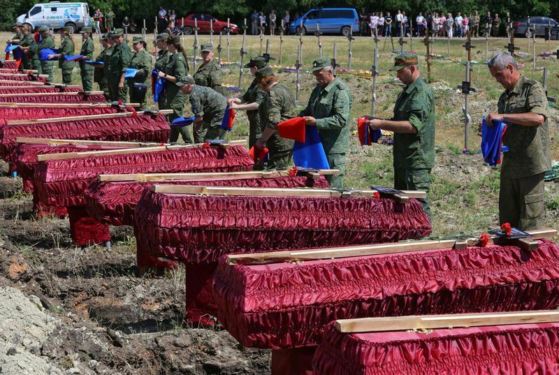ロシア占領中のルハンスクで、親ロシア派の身元不明の兵士58人の葬儀。ロシアと自称ルハンスク共和国の旗を棺にかけようとしている。2022年7月12日