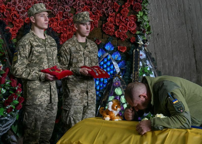 女性兵士オルガ・シモノバさんの棺を抱える同僚のウクライナ兵士。彼女は2014年ロシアを去ってウクライナのために戦いにやってきたが、ドネツク地方で殺された。2022年9月16日キーウでの葬儀。