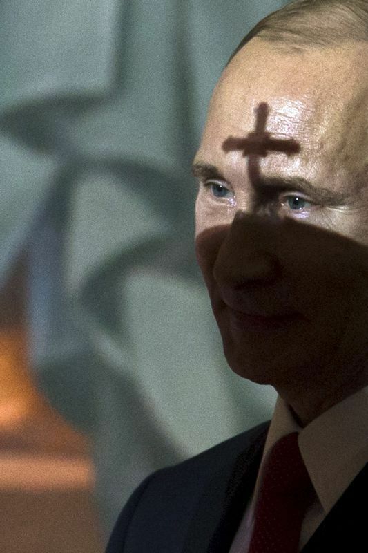 キリル総主教のミトレ（聖職者の帽子）の影がプーチン氏の顔に映っている。2015年。