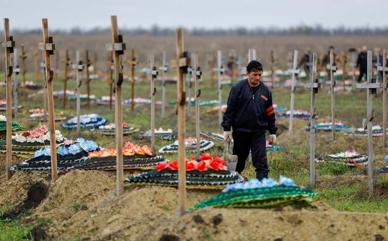 ロシア支配下のルハンスクにある墓の前を歩く墓堀り人。2022年11月11日。墓も墓地も増える一方だ。東アジアの近未来の姿かもしれない。