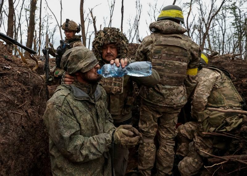 バフムート近くで、ウクライナ兵士が最近攻撃で獲得した陣地で捕えたロシア軍人に水を与える。5月11日