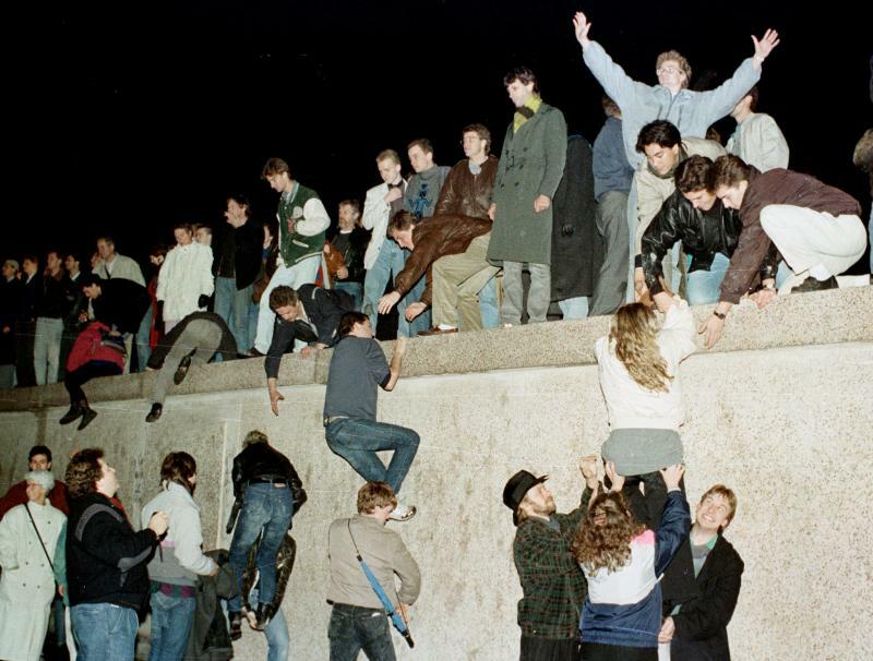 1989年11月10日、東ドイツ国境の開通を祝い、ブランデンブルク門のベルリンの壁に登る東ドイツ国民。