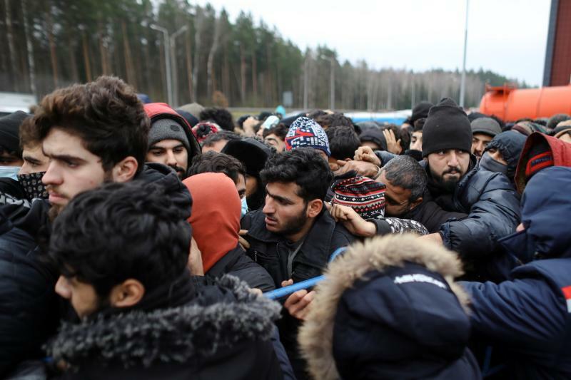 2021年11月21日、ポーランドの国境近くのベラルーシのグロドノ地方。物流センターの外で食料の受け取りを待ちながら、移民たちが押し寄せる。南出身の容姿の人たちである。