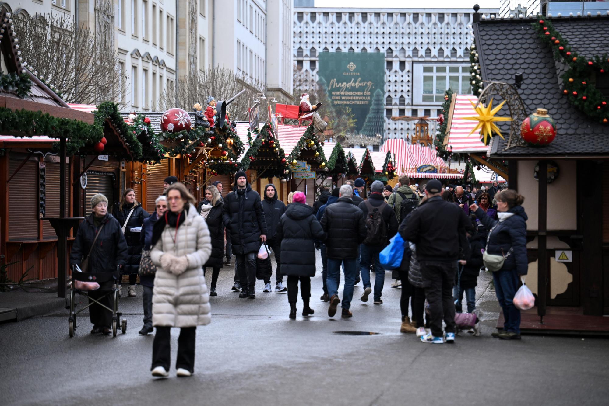 12月22日、マクデブルクのクリスマス市「アルターマルクト」で、閉鎖した屋台を通り過ぎる人々。犠牲者のご冥福を祈りたい。