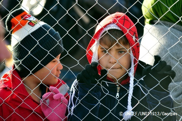 難民のための施設の近くにあるフェンスから外を眺める男の子たち。 (C) UNICEF