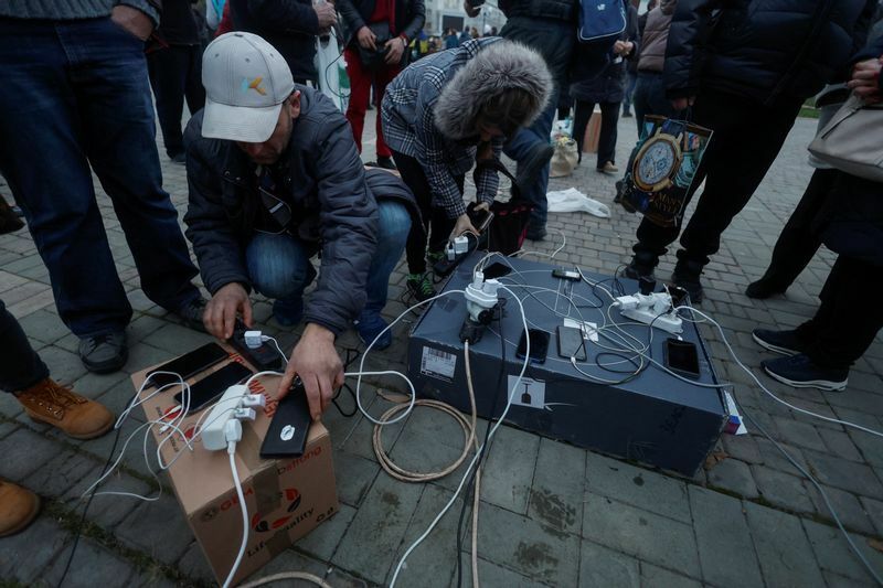 屋外の発電機でスマホに充電しているウクライナの市民