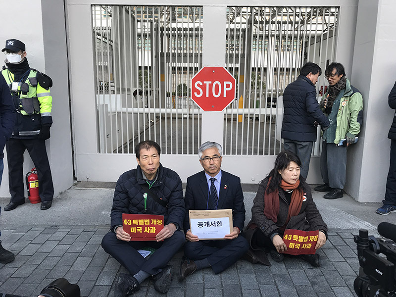 在ソウル米国大使館の正門前に座り込む「済州4.3事件犠牲者遺族会」の梁閠京（ヤン・ユンギョン、中央）会長たち。大使館を警備する警察側から、暴力的な排除や警告などは一切なかった。7日、筆者撮影。