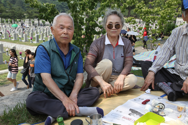 ペク・ナムサンさんの墓碑と、4歳年下の弟、ペク・ナミョンさん(86、左)。右は妹だ。