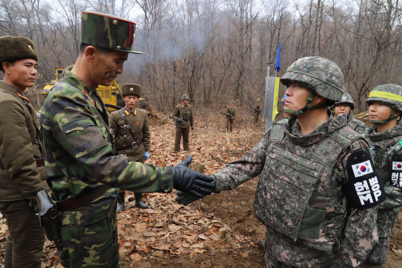 11月22日、互いに地雷を除去し道路を作ってきた南北の軍人たちが、軍事境界線付近で握手している。写真は国防部提供。
