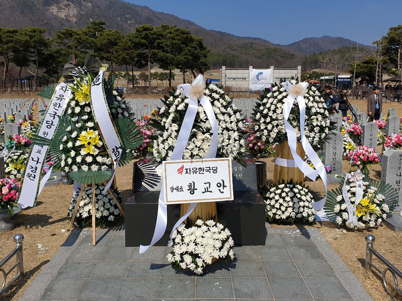 黄教安代表は慰霊碑の前に花輪を置いた。左の文大統領の花輪の前には、同じ自由韓国党の羅院内代表の花輪を置き遮った。右の李洛淵総理の花輪の名札を抜き取られている。22日、筆者撮影。