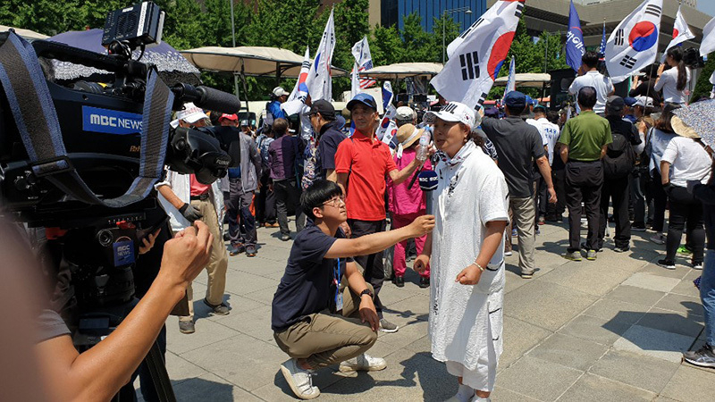 韓国メディアの取材に答えるデモ参加者。今の豊かな韓国を作ったのは保守だと力説していた。25日、筆者撮影。