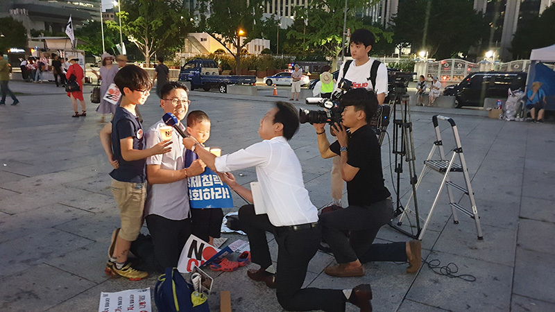 子連れで参加した市民にインタビューする韓国メディア。