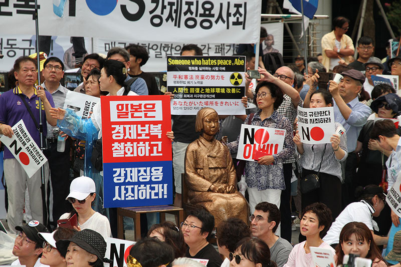 3日のデモは、旧日本大使館前で行われた。「平和の少女像」がある場所だ。プラカードには「日本は経済報復を撤回し強制徴用を謝罪せよ」とある。3日、筆者撮影。