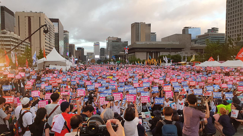 週末ごと5週に続けて行われている「安倍糾弾デモ」参加者の手に、「韓日軍事情報協定破棄せよ！」と書かれたプラカードを掲げている。8月15日、筆者撮影。