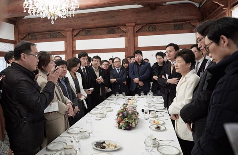 「権力に従順なメディア」のイメージを決定的にした写真。17年1月、弾劾決議案の可決により職務停止となった朴槿恵大統領(当時)の前で、疑惑を追及することもなく神妙に手を組む記者たち。青瓦台提供。
