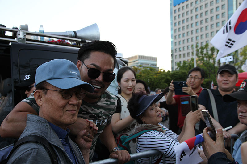 光化門広場には、チャンネル登録者数が20万人を超える人気「反中」ユーチューバー（サングラスの人物）も表れ、ファンの写真攻めにあっていた。「韓国は中国に乗っ取られている」とする人物だ。3日、筆者撮影。