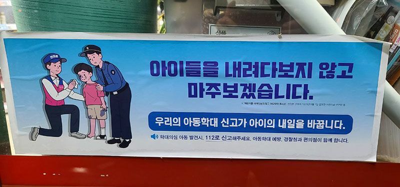 韓国のコンビニに貼られているステッカー「子どもを見下ろさず目線を合わせます。私たちの児童虐待通報が子どもの明日を変えます」と書かれている。今年8月、筆者撮影。