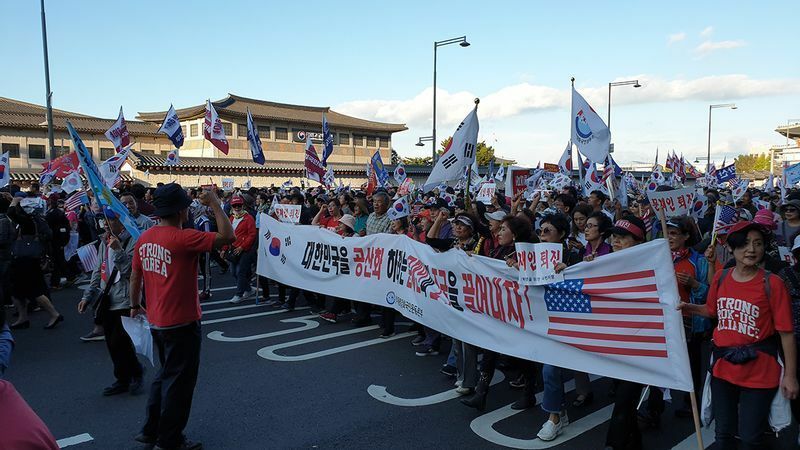 「大韓民国を共産化する文在寅とチョ・グクを引きずり下ろせ！」と書かれた垂れ幕を持つ市民たち。「太極旗デモ」での一幕だ。2019年10月3日、筆者撮影。