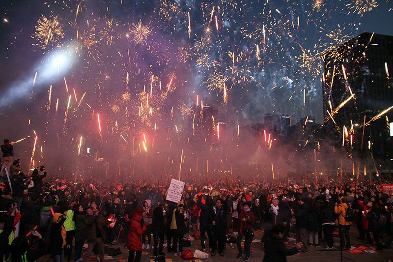 朴槿惠大統領の罷免が決まった翌日の17年3月11日、ソウル市内の光化門広場で花火を打ち上げ祝う市民たち。17年3月、筆者撮影。