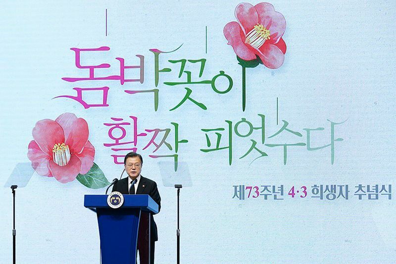 演説する文大統領。椿の花は済州4.3の象徴だ。