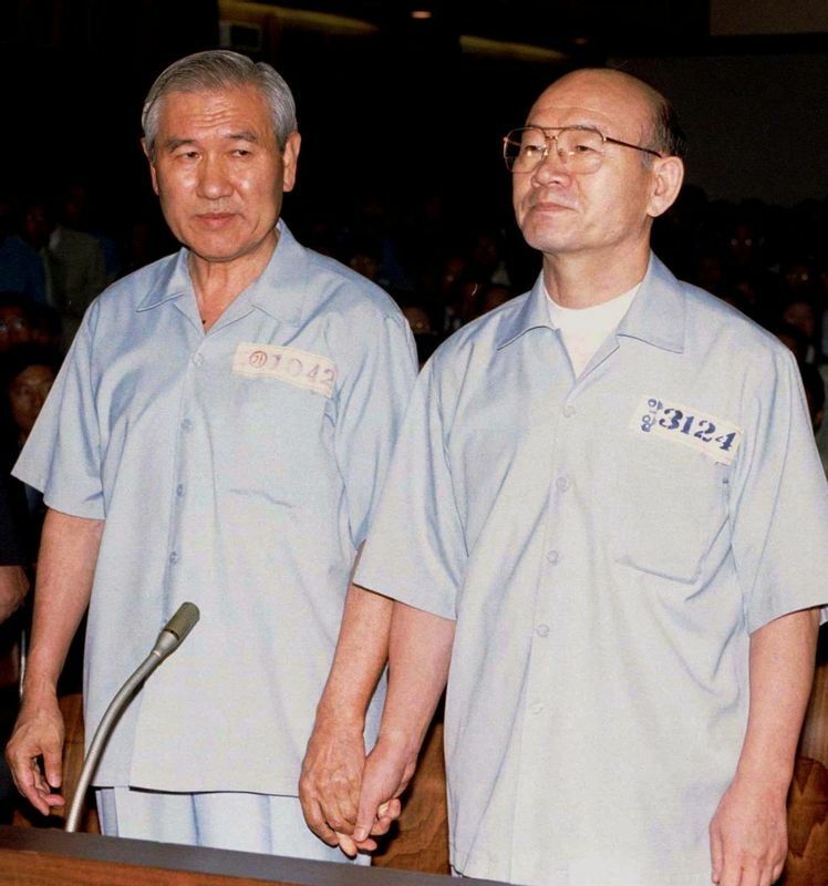 1996年、法廷で手をつなぐ盧泰愚（左）、全斗煥両氏。