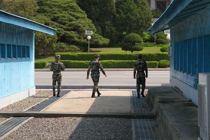 19年5月1日に訪問した際、北朝鮮の兵士3人が記者団の姿をカメラに収めていった。非武装だ。腕章には「民事警察」の文字が。現在は南北35人ずつが非武装で警備にあたる。筆者撮影。