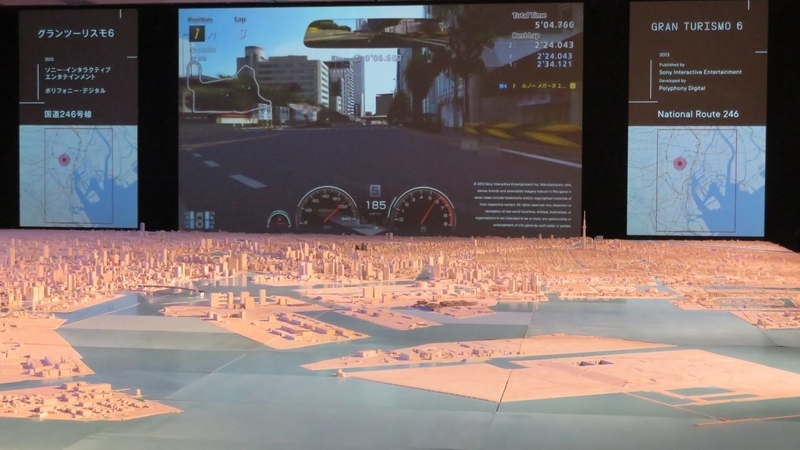 巨大スクリーンに映し出された「グランツーリスモ6」。左右両端にある地図で、ゲームの舞台となっている場所も教えてくれる