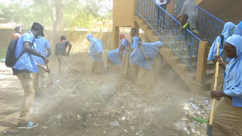 ほこりが舞う校内を清掃中の生徒たち（写真提供:JICA）