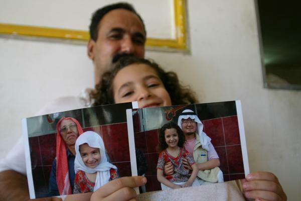 橋田さんと小川さんの写真を持つイラク人少女
