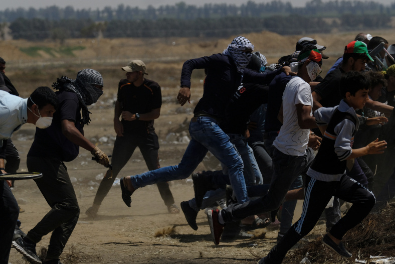 イスラエル軍の実弾射撃や催涙ガス弾を避けようとする抗議者達。ガザにて。