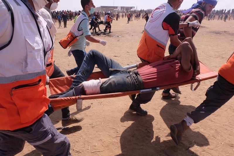 狙撃による負傷者を搬送する赤新月のスタッフら。ガザにて。