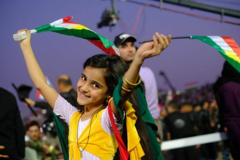 クルド民族を象徴する旗を手にポーズをとる少女　イラク北部アルビルにて筆者撮影