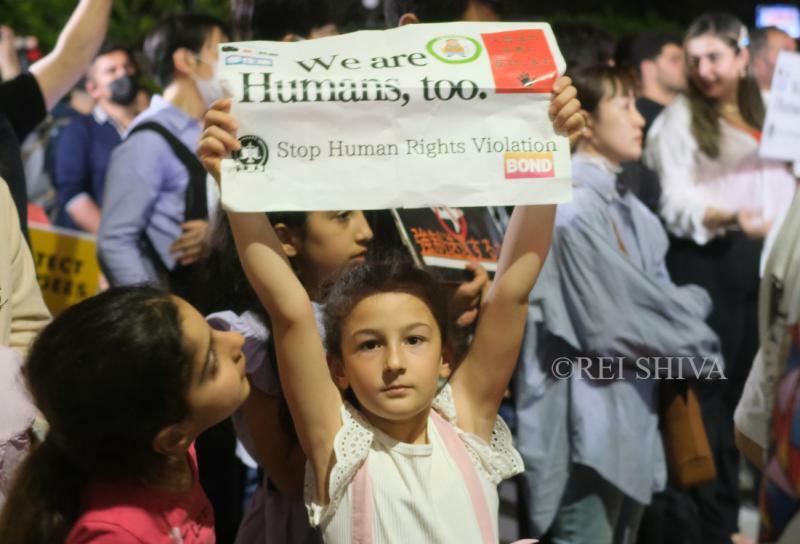 入管法改悪反対の国会前集会で「私達も人間だ」とのプラカードを掲げる少女　筆者撮影