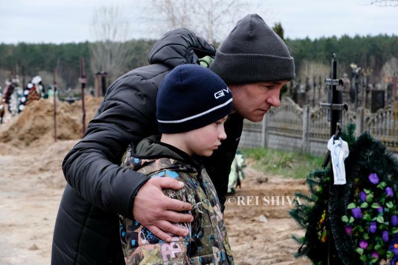 ロシア軍の攻撃で殺された母親の墓の前に立つ少年　ウクライナ中北部ブチャにて筆者撮影