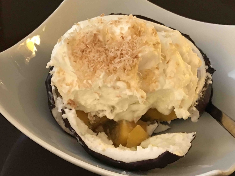 デザートは、ココナッツの殻に見立てたメレンゲの器にフレッシュなマンゴーとレモンのジュレ、そしてサクサクのココナッツフレークを詰め、最後にココナッツ風味のホイップクリームを載せて完成