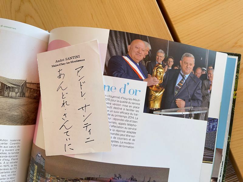 イシー・レ・ムリノ市の歴史を綴った本が、レストランの完成を祝してサンティニ市長から直筆サインとともに贈られた。写真でトリコロールのたすきをかけているのが市長