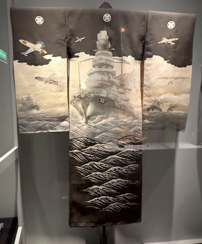 1932年から1945年の間に製作されたとされる男児のお宮参りのための晴着。戦艦と日の丸の飛行機が描かれているところがいかにも時勢を物語っている。ヴィクトリア&アルバートミュージュアム所蔵