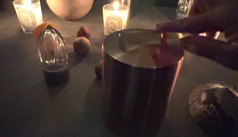 「触る」のコーナー、薄明かりに浮かび上がる「開化堂」八木隆裕さん作の茶筒。その左にあるのは、「アトリエ・ジョルジュ」の柑橘類を絞る道具。手拭きガラスでできている