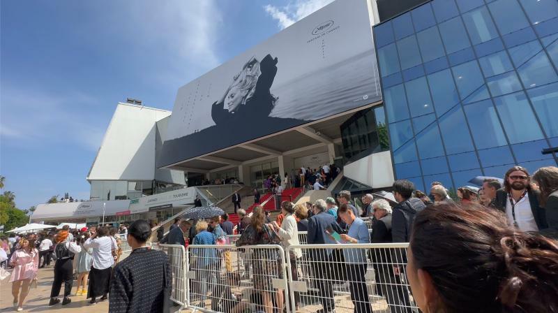 メイン会場となる「パレ・デ・フェスティヴァル・エ・デ・コングレ」には、上映会を待つ人々の列が長く続いている。今年の映画祭のポスターの顔はカトリーヌ・ドヌーヴ。（写真:筆者撮影）