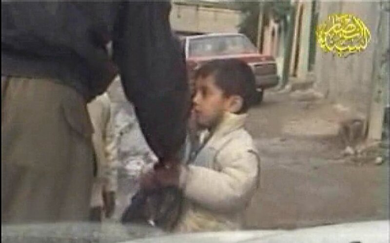 イスラーム過激派武装勢力の戦闘員に施しの肉を押し付けられて恐怖で硬直する小児。出典：アンサール・スンナ軍。